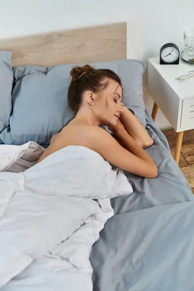 A young woman peacefully rests in stylish lingerie on a neatly made bed. — Stock Photo