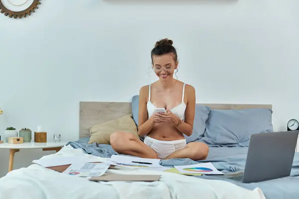 A young woman smiles while sorting documents on her bed. — Stock Photo