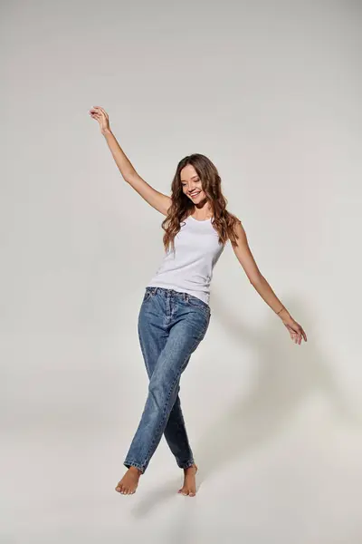 A joyful young woman dances barefoot, showcasing her carefree spirit and style. — Stock Photo
