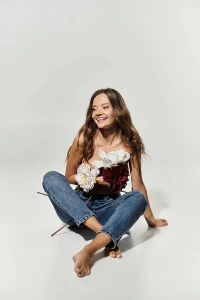 Una joven alegre posa graciosamente, sonriendo mientras sostiene flores frescas. — Stock Photo