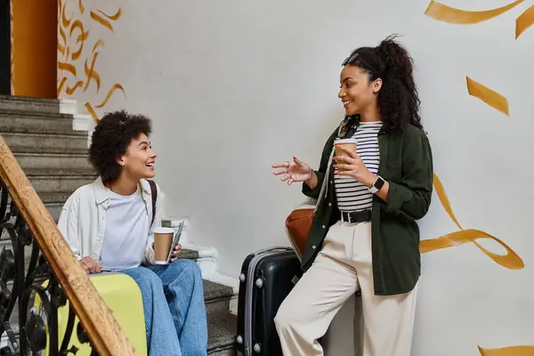 Deux femmes heureuses partagent le rire et le café tout en profitant de leur aventure de voyage dans une auberge conviviale. — Photo de stock