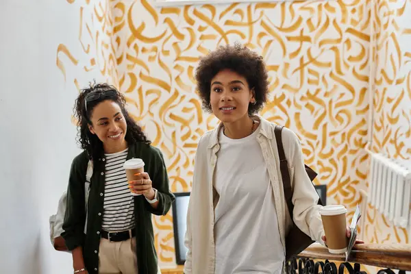 Un couple heureux profite de leur temps dans une auberge dynamique, riant en montant les escaliers avec café à la main. — Photo de stock