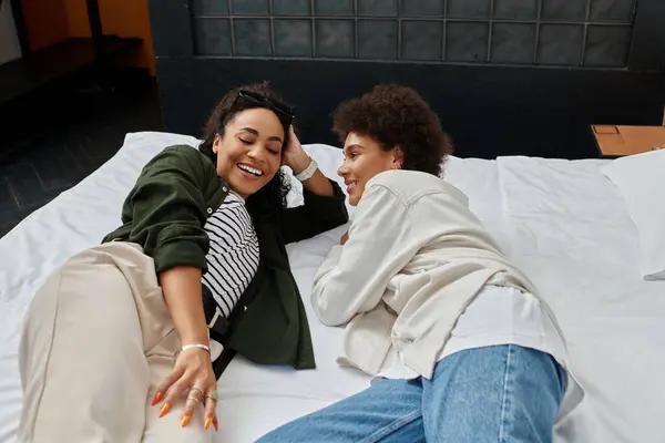Two happy women share laughter and connection while relaxing in their cozy hotel room. — Stock Photo