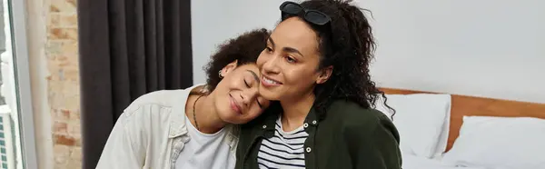 Two happy women embrace in their hotel room, cherishing moments of love and connection during their trip. — Stock Photo