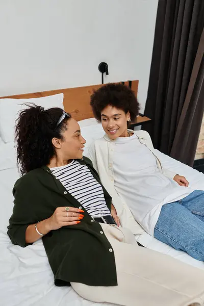 Two joyful women relax in their hotel room, sharing smiles and laughter while enjoying each others company. — Stock Photo