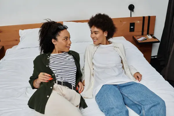 Two happy women share laughter and connection while relaxing in their cozy hotel room. — Stock Photo