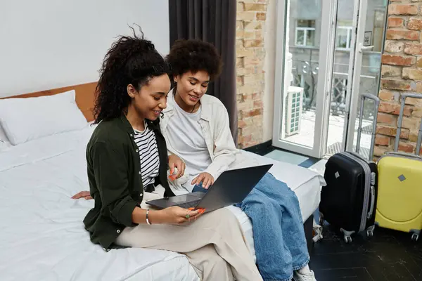 Una pareja feliz revisa los planes de viaje juntos, rodeados por su acogedora habitación de hotel. - foto de stock