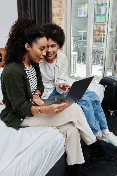 A happy couple shares laughter and joy while exploring travel plans on their laptop in a cozy hotel setting. — Stock Photo