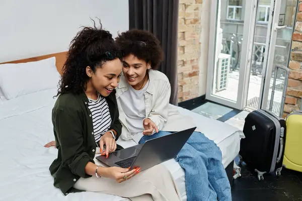 A joyful couple shares laughter while exploring travel plans together in their cozy hotel room. — Stock Photo
