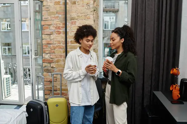 Ein glückliches Paar teilt Momente zusammen in seinem Hotelzimmer, nippt an Getränken und genießt die Gesellschaft des anderen. — Stockfoto