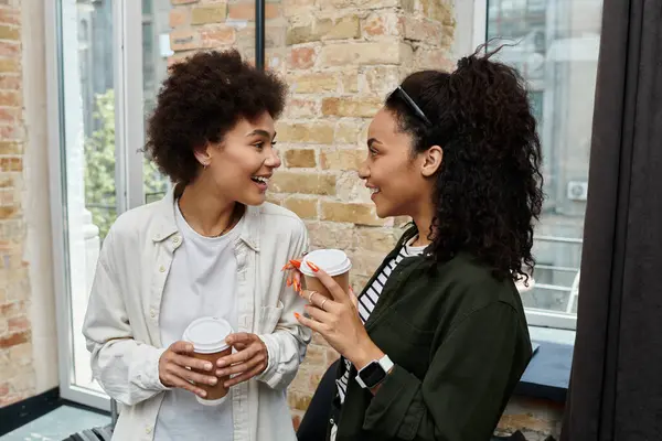 Two happy women share laughter and coffee, enjoying precious moments during their hotel stay. — Stock Photo