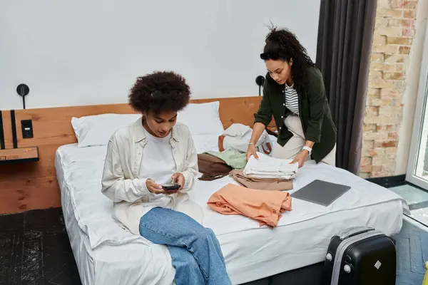 A happy couple enjoys quality time together, folding clothes and sharing laughs in their stylish hotel room. — Stock Photo