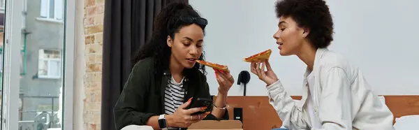 Um casal alegre compartilha pizza e risos em seu quarto de hotel enquanto desfruta uns dos outros companhia. — Fotografia de Stock