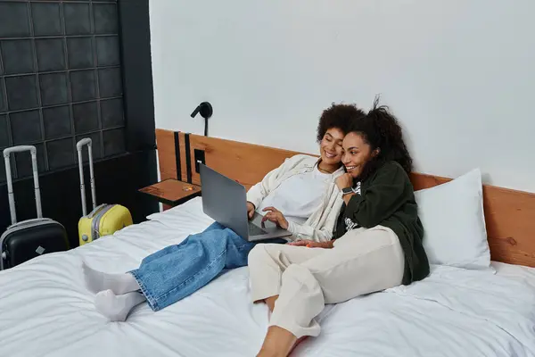 A joyful couple relaxes on a bed, sharing laughter and warmth while planning their adventures. — Stock Photo
