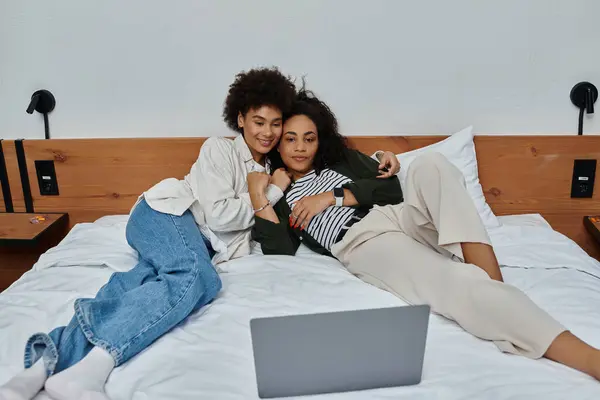 Two women relax on a bed, sharing laughs and smiles while exploring their favorite shows together. — Stock Photo