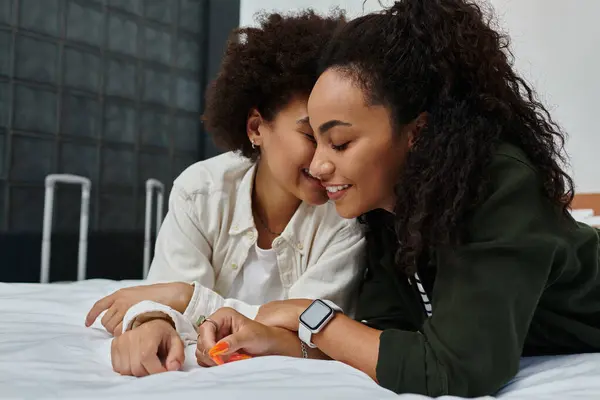 Um casal alegre compartilha riso e carinho enquanto relaxa em sua cama de quarto de hotel. — Stock Photo