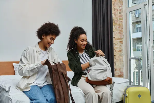 Two happy women explore their bags, enjoying a special moment together in their hotel stay. — Stock Photo