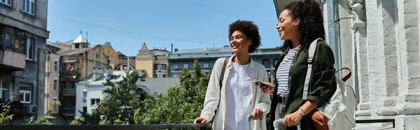 Two women enjoy their travel adventure together while soaking up the vibrant city from their balcony. — Stock Photo