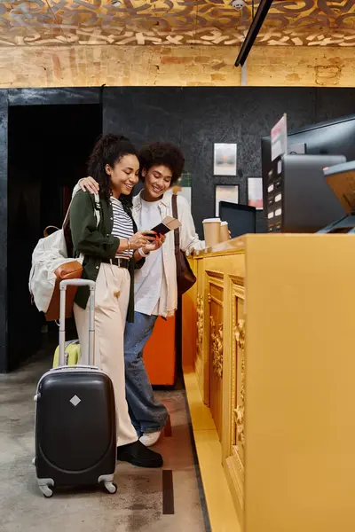 A joyful couple reviews their travel details while checking into a welcoming hostel. — Stock Photo