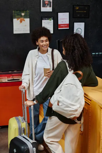 A happy couple engages at the hostel reception, surrounded by luggage and warm smiles. — Stock Photo