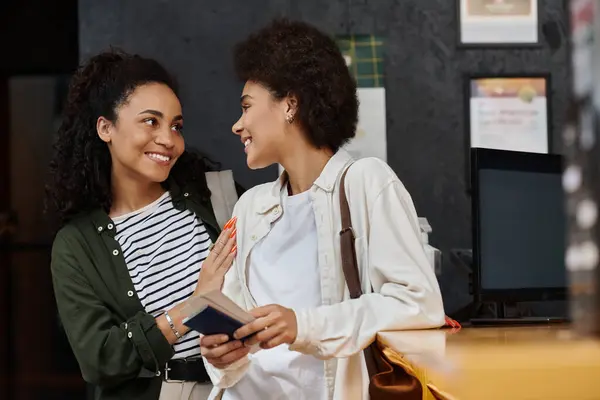A joyful couple laughs together while checking in at a hostel reception desk on their travel adventure. — Stock Photo