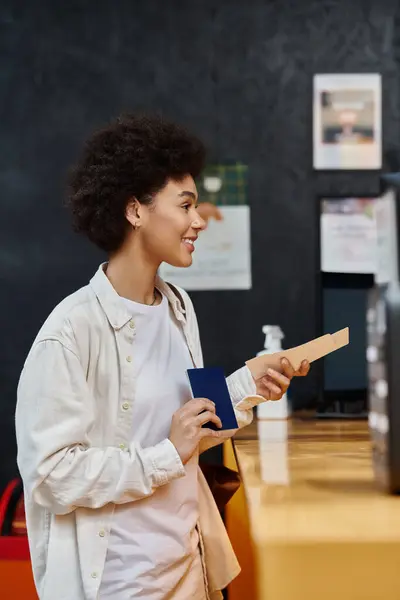 A happy girl checks in at a hostel reception, smiling for her upcoming adventure. — Stock Photo