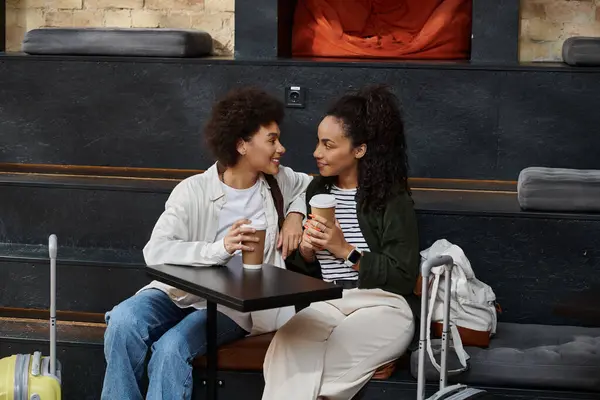 Ein fröhliches Paar genießt seine Zeit in einem Hostel-Café und teilt Lächeln und warme Getränke. — Stockfoto