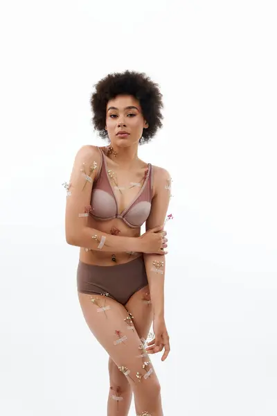 Beautiful curly haired woman posing with flowers on body and underwear. — Stock Photo