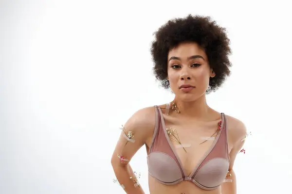 Pretty curly haired woman posing with flowers on body and underwear. — Stock Photo