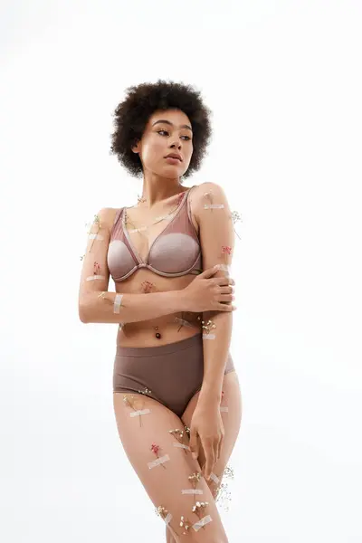 Alluring curly haired woman posing with flowers on body and underwear. — Stock Photo