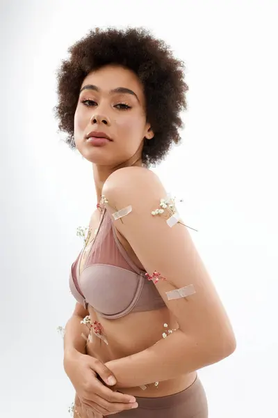 Attractive curly haired woman posing with flowers on body and underwear. — Stock Photo
