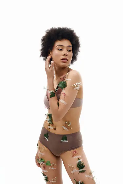 Appealing african american woman with curly hair with flowers on her body in pastel underwear. — Stock Photo