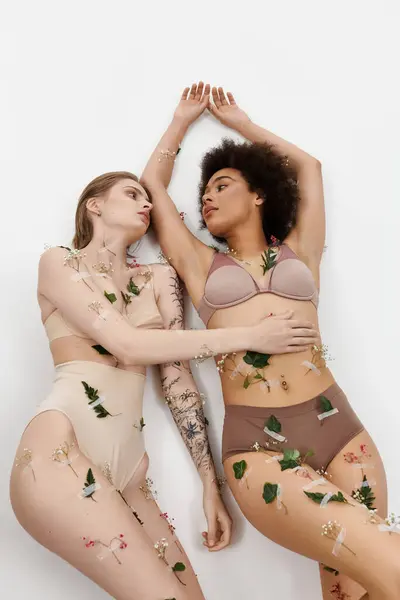 Two women embrace, decorated with flowers and leaves, radiating love and connection. — Stock Photo