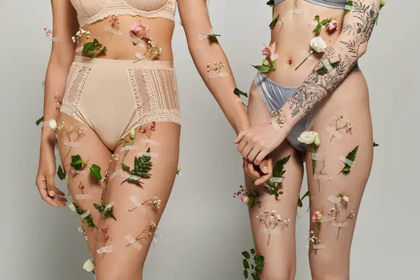 Due donne condividono un momento tenero, adornate di fiori e verde, celebrando il loro amore. — Foto stock