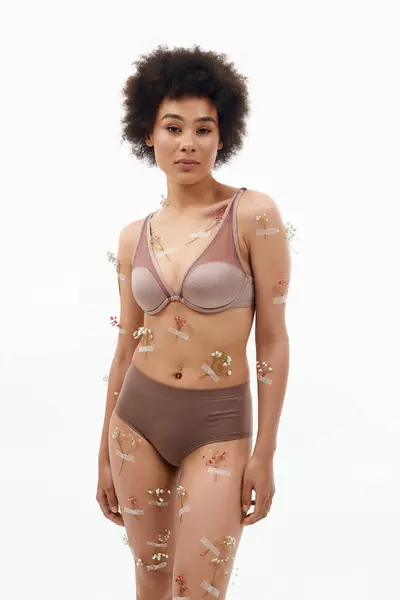 Una donna gioiosa in posa con fiori sul corpo e biancheria intima. — Foto stock