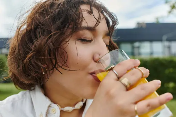 Eine fröhliche Frau nippt an einem erfrischenden Getränk und sonnt sich in der Wärme eines sonnigen Sommerpicknicks. — Stockfoto