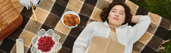 A young woman in a white shirt relaxes on a picnic blanket, savoring a summer day filled with berries and pastries. — Stock Photo