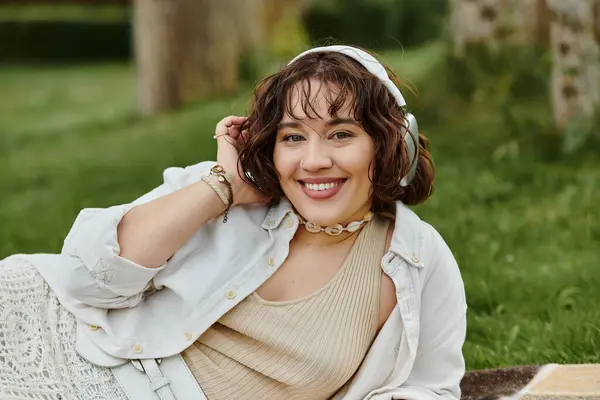 A cheerful young woman in a white shirt enjoys a summer picnic, soaking in the sunshine and nature. — Stock Photo