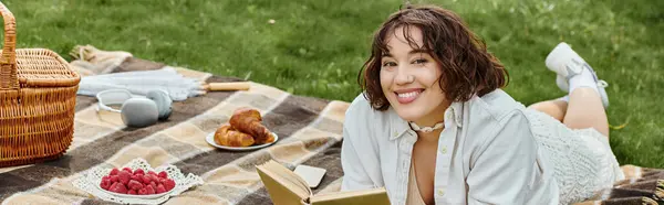 A young woman in a white shirt relaxes on a picnic blanket, savoring summer and a good book. — Stock Photo