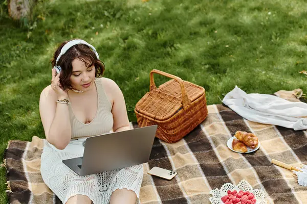 A young woman relaxes on a blanket during summer, enjoying the warmth and music at her picnic. — Stock Photo