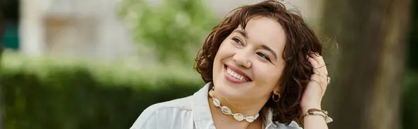 A cheerful young woman relaxes and smiles, basking in the warm sunshine of a green park during summer. — Stock Photo