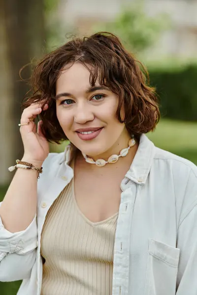 A cheerful young woman revels in the warmth of summer, basking in the lush greenery of the park. — Stock Photo