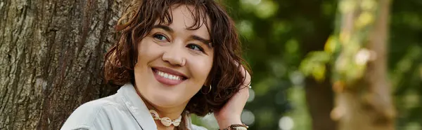 Eine fröhliche junge Frau genießt ihre Zeit in einem üppig grünen Park und sonnt sich in der warmen Sommersonne. — Stockfoto