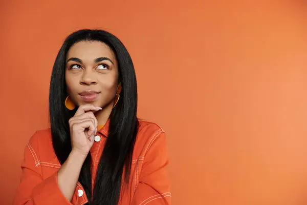A woman contemplates with a playful expression in front of a bright backdrop. — Stock Photo