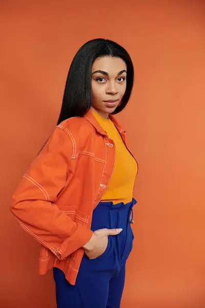 A confident woman showcases her vibrant outfit in front of a striking backdrop. — Stock Photo