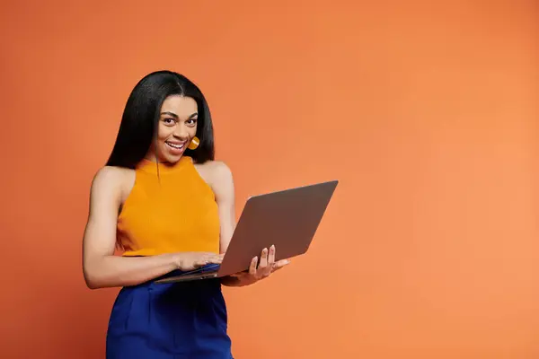 Uma jovem alegre se envolve com seu laptop, irradiando positividade em um ambiente vibrante. — Fotografia de Stock