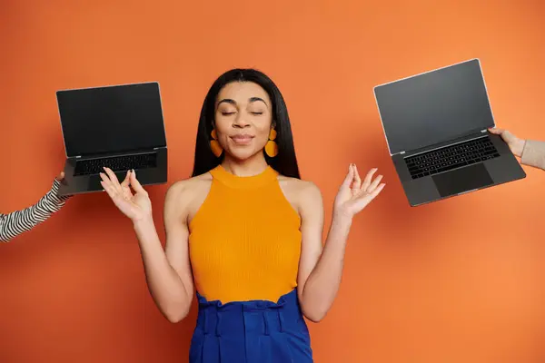 A poised woman enjoys a light hearted moment while balancing laptops. — Stock Photo