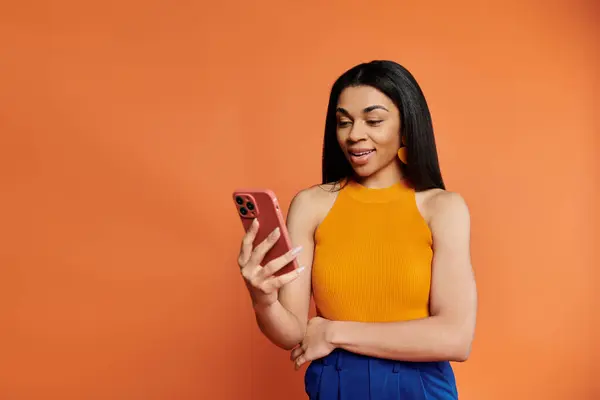 A cheerful woman interacts with her phone, emanating positivity and style. — Stock Photo
