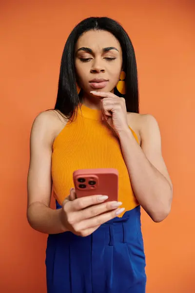 Una mujer interactúa pensativamente con su teléfono inteligente, perdido en la contemplación. - foto de stock