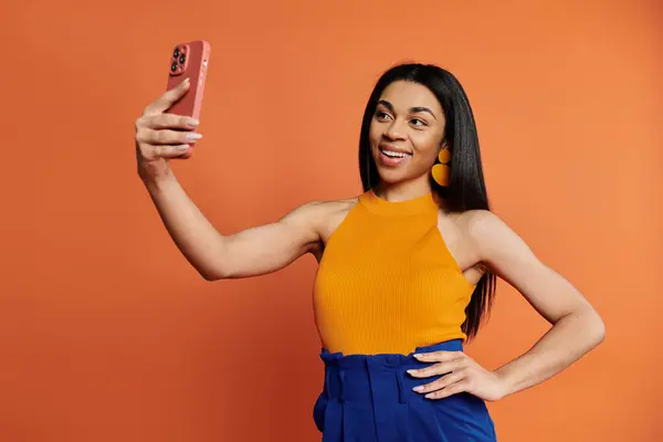 Smiling woman captures a joyful moment with her phone in a colorful setting. — Stock Photo
